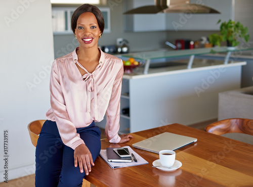 Confident young businesswoman  leaning on her dining room table at home