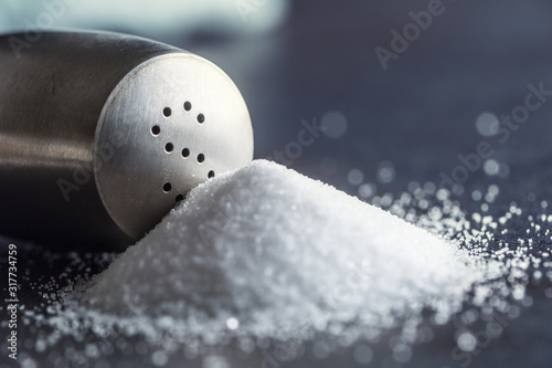 Tableau sur toile Spilled salt with staniless salt shaker - Closeup