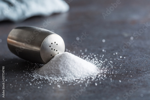 Spilled salt with staniless salt shaker - Closeup photo