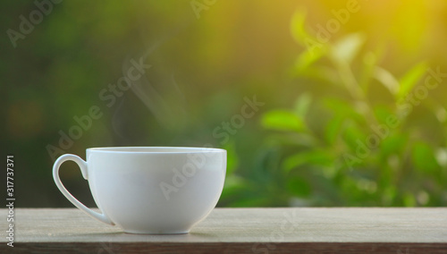coffee cup on wooden table with nature on background