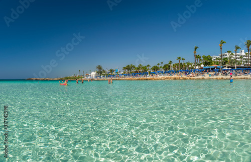 CYPRUS, NISSI BEACH - MAY 12/2018: Tourists relax and swim on one of the most popular beaches on the island. photo