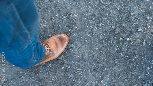 Bota de cuero con pantalón vaquero  pisando un suelo arenoso photo