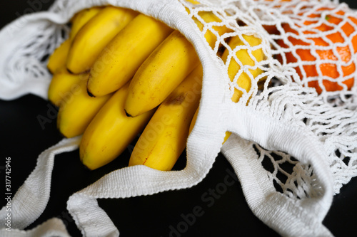 white string mesh bag filled with fruit isolated on a black background