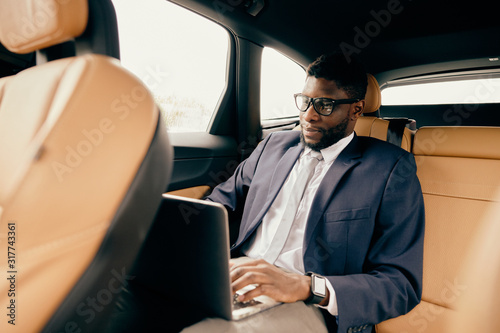 Businessman working on the laptop during a car ride. © Anton