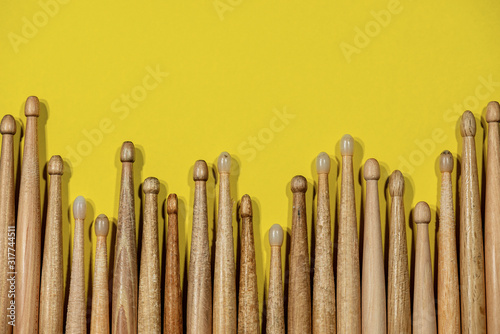 Close-up of many wooden drumsticks on a yellow background with copy space. Percussion instrument photo