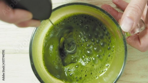 Woman making matcha tea, mixed water with matcha powder, slow motion