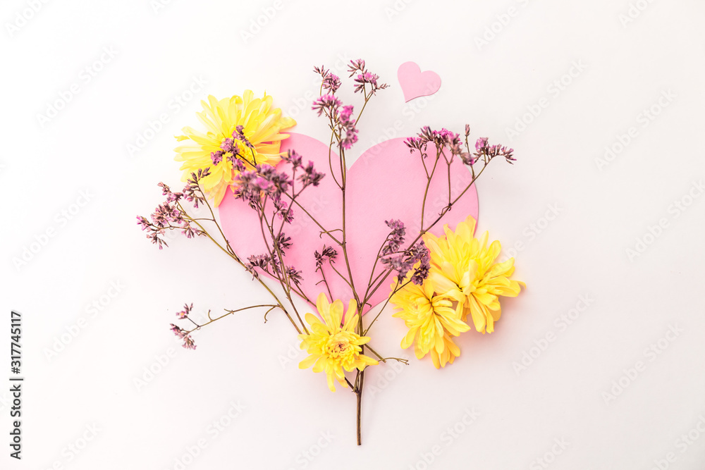 A large pink hear decorated with small pink flowers and yellow chrysanthemums on a white background