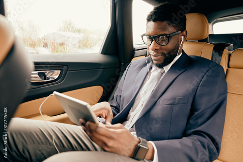 Man scrolling through the tablet screen during car ride. © Anton