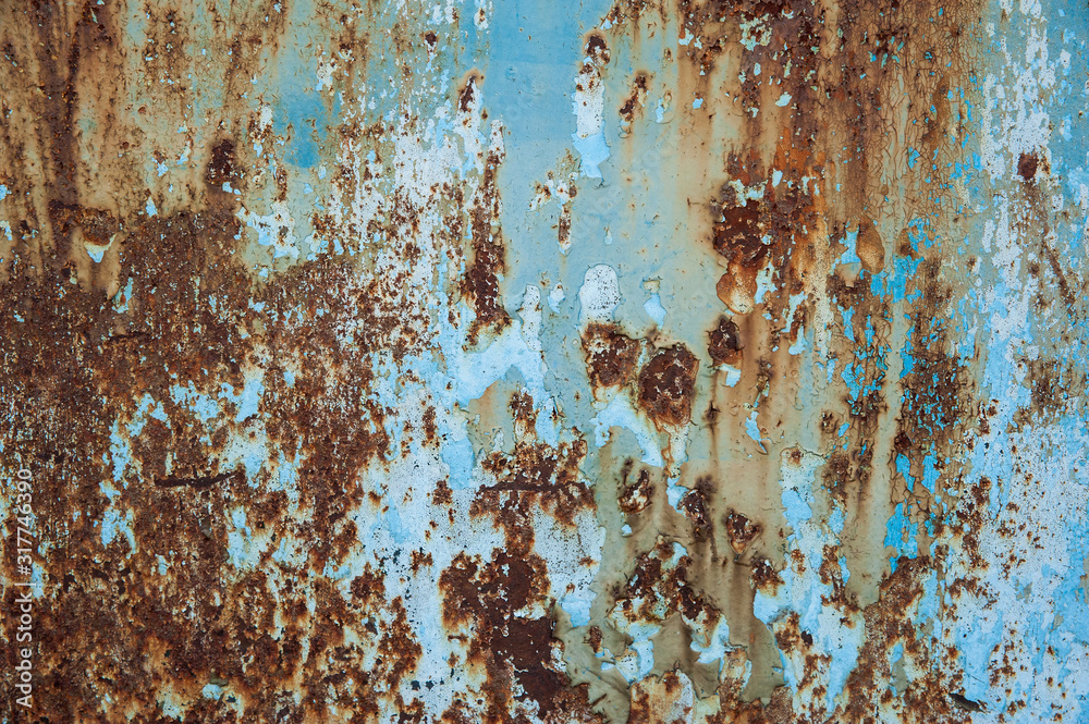 The remnants of light blue paint on a heavily corroded old metal surface. Abstract background, texture. The remnants of light blue paint on a heavily corroded old metal surface. Abstract background, texture.