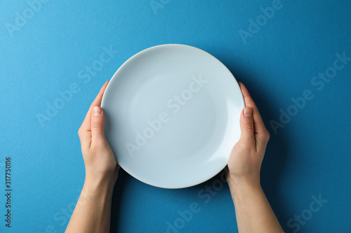 Fotografie, Obraz Female hands hold plate on blue background, top view