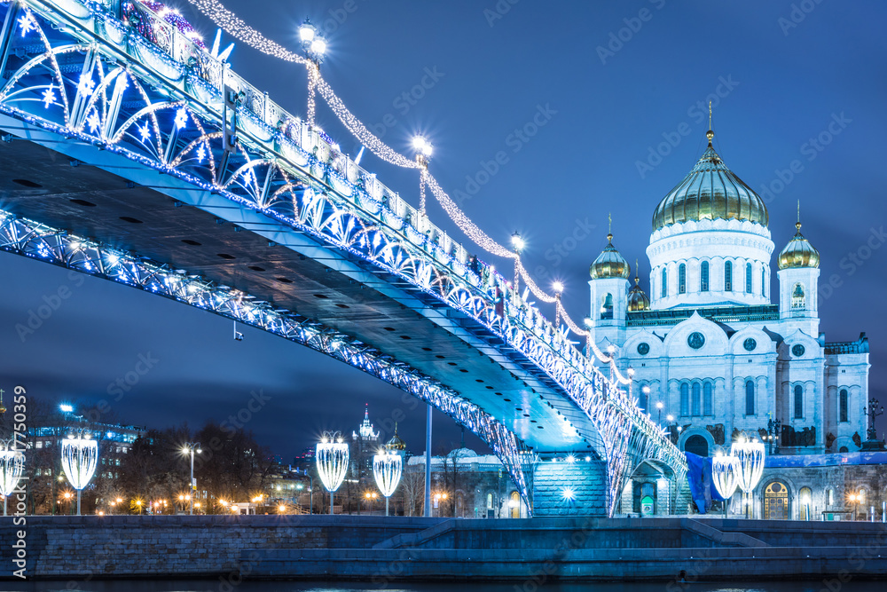 The beautiful Patriarshy Bridgeand Cathedral of Christ the Saviour with christmas illumination. The symbol of Orthodox church in Russia in the rays of setting sun. View from the embankment of Moskva