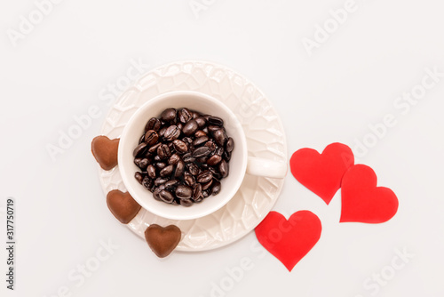 Top View of Cup of Coffee grains with heart shaped chocolate cookies and red paper hearts on white   background. Valentines day concept © Ivan