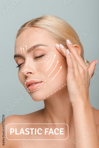 young beautiful woman with closed eyes touching face with plastic surgery marks isolated on grey photo
