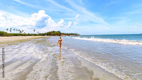 Beautiful girl walking on the beach in Sri Lanka with swim suit at the Indian Ocean.