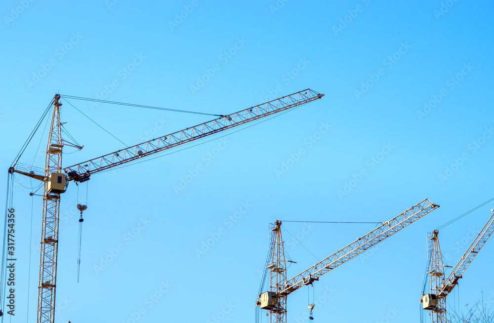 construction cranes against the blue sky. Place under the text, copy space. Concept construction, construction