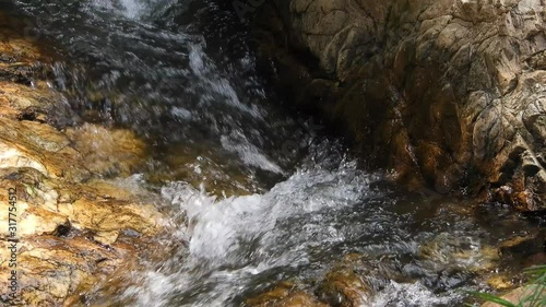 Crystal clear fresh mountain waterfall crocodile river water sparkling and flowing over rocks and pebbles in the background at the walter sisulu national botanical gardens in roodepoort, South Africa. photo