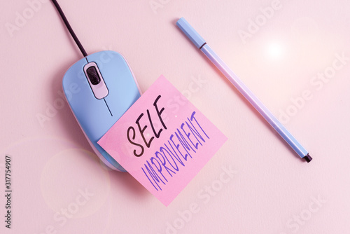 Writing note showing Self Improvement. Business concept for process of making yourself a better or more knowledgable Empty note paper and computer mouse with stationary on pastel backdrop photo