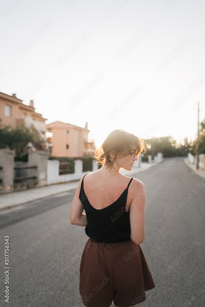 girl walks through the city streets at sunset