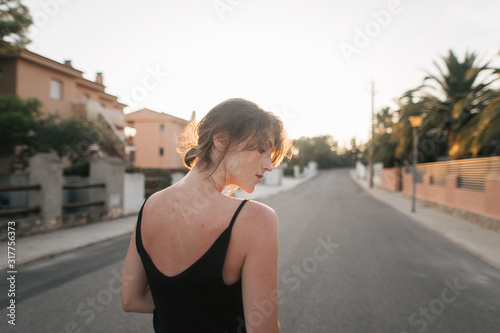 girl walks through the city streets at sunset