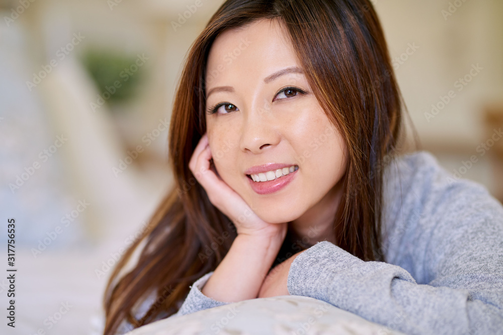 Smiling young Asian woman relaxing on her bed Smiling young Asian woman relaxing on her bed