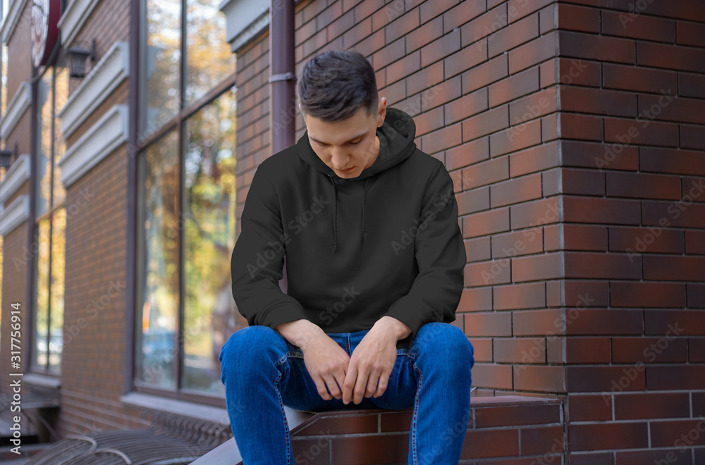 Front view of a black sweatshirt template on a young guy in blue jeans. Front view of a black sweatshirt template on a young guy in blue jeans.