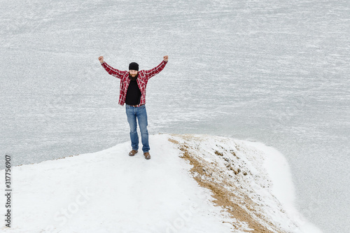 bearded man looks at a frozen lake in winter
