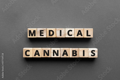 Medical cannabis - words from wooden blocks with letters, medical marijuana (MMJ) cannabis and cannabinoids concept, top view gray background
