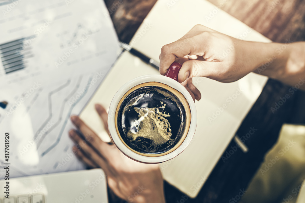 Obraz premium Hand hold cup of coffee between working.Drink of coffee