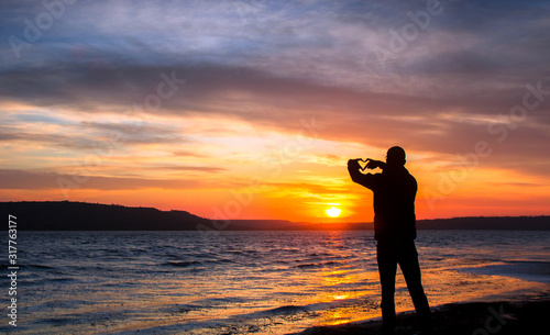 silhouette of a happy unrecognizable man in love at sunset on the lake