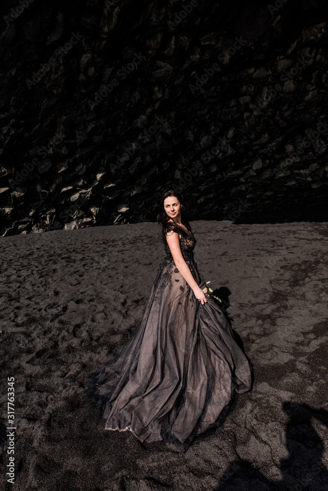 bride in black clothes stands in a black cave on a black sand beach near the Atlantic Ocean in Iceland bride in black clothes stands in a black cave on a black sand beach near the Atlantic Ocean in Iceland