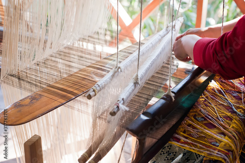 Woman weaving silk in traditional way at manual loom. Laos