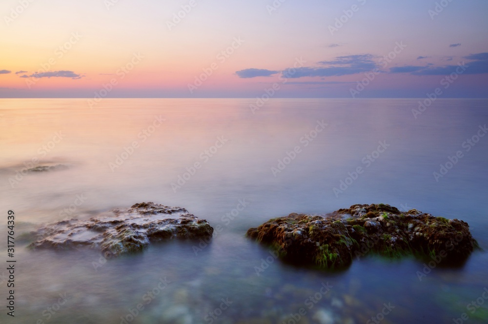 Beautiful pink sunset and water stones over Black sea rocky coastline in Crimea