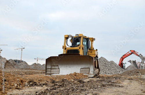 Dozer with buckets at construction site. Bulldozer during land clearing, grading, pool excavation, utility trenching and foundation digging. Possible granularity