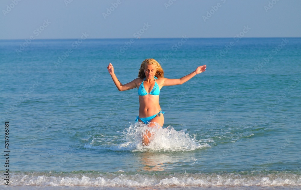 Young woman in sportswear running near still sea edge and smiling Young woman in sportswear running near still sea edge and smiling