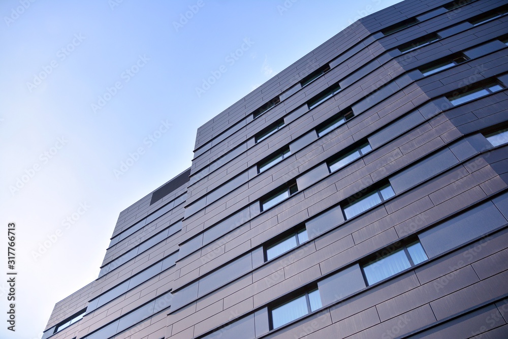 A view at a straight facade of a modern building with a dark grey facade.