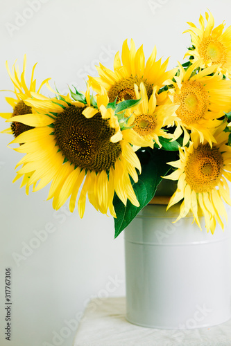 bouquet of bright yellow sunflower flowers in a retro vase on a white background