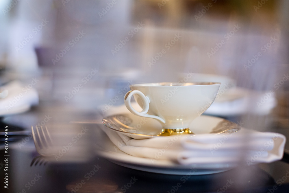 a white tea cup with a gold border is on the table