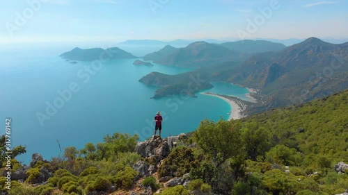 Aerial shot flying over man standing on the edge of a cliff in the summer. Drone shot