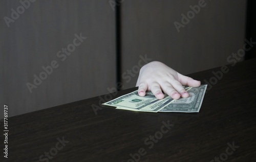 Child takes the money. The hand of the child stealing money from the table