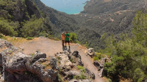 Aerial shot flying over couple standing on the edge of a cliff in the summer. Drone shot