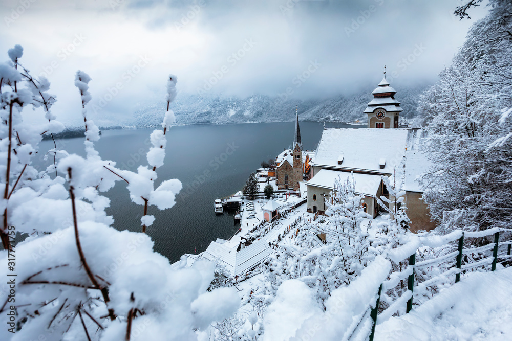 Obraz premium Blick auf das eingeschneite Dorf Hallstatt in Österreich im Winter mit Schneebedeckten Bergen