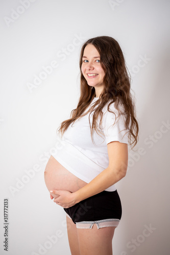 The young beautiful pregnant woman experiences strong emotions on a white background
