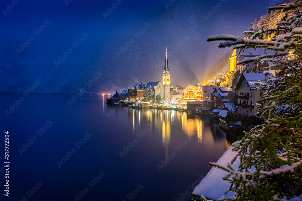 Bick auf das winterliche Hallstatt am Abend mit Schnee und warmer Beleuchtung, Österreich Bick auf das winterliche Hallstatt am Abend mit Schnee und warmer Beleuchtung, Österreich