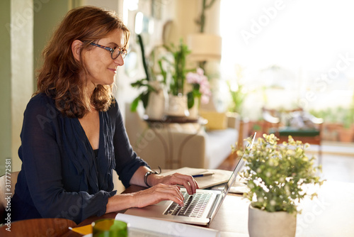 Smiling mature female entrepreneur using a laptop at home © marvent