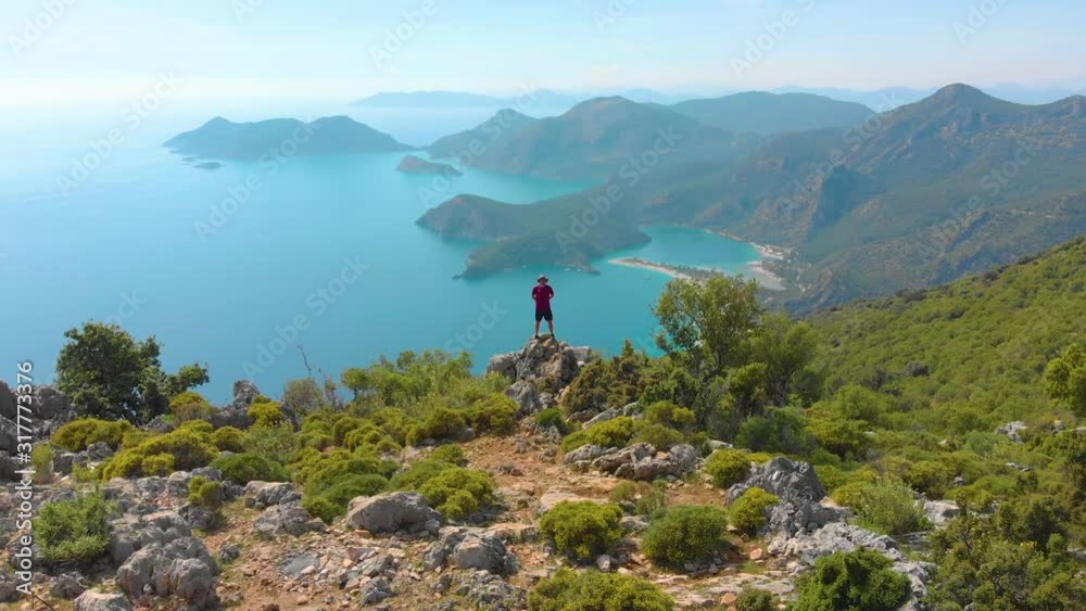 Aerial shot flying over man standing on the edge of a cliff in the summer. Drone shot Aerial shot flying over man standing on the edge of a cliff in the summer. Drone shot