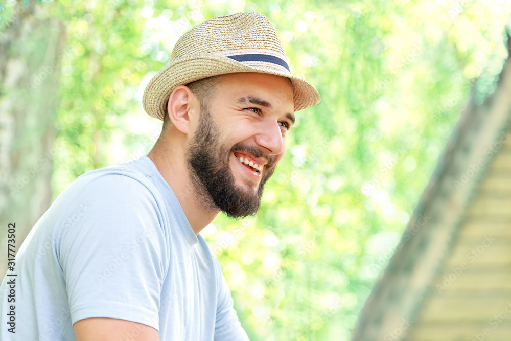 smiling bearded man in a hat and a t-shirt in nature