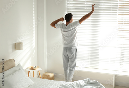 Man near window in bedroom. Lazy morning