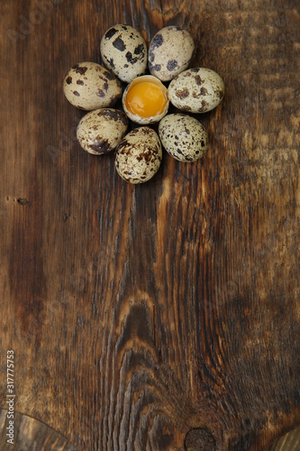  Organic quail eggs and yolk in the form of a flower on a wooden rustic background with copy space for text. Farm products. Easter holiday. Flat lay. Top view. Vertical photo.