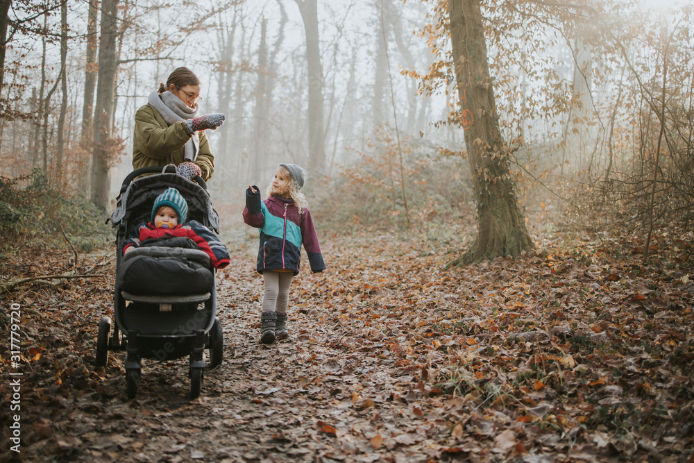 Mother with daughters during forest walk in autumn