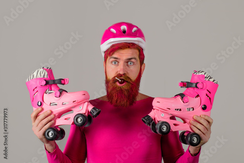 Man with roller skates and lollipop. Sport helmet. Active sport. Roller skating ride. Healthy lifestyle. Bearded man with roller-skates. Vacation. Protective sport helmet. Protective sport equipment. photo